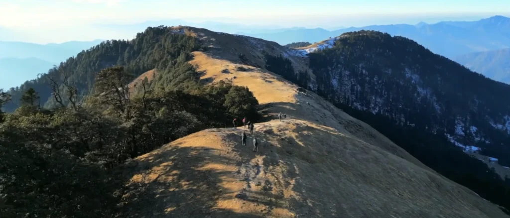 Brahmatal Trek ridge trail Uttarakhand, trekkers walking on Himalayan mountain ridge, Brahmatal winter trek landscape, scenic Himalayan trekking route India, best trekking trail in Uttarakhand