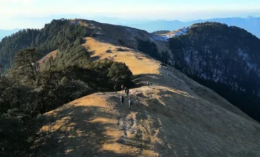 Brahmatal Trek ridge trail Uttarakhand, trekkers walking on Himalayan mountain ridge, Brahmatal winter trek landscape, scenic Himalayan trekking route India, best trekking trail in Uttarakhand