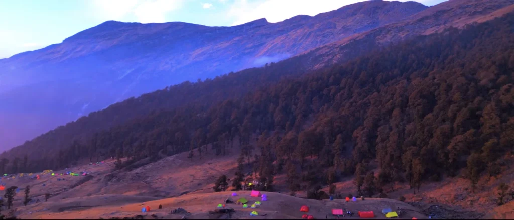 Brahmatal Trek campsite with Himalayan forest, colorful tents during Brahmatal winter trek, scenic mountain campsite Uttarakhand, Himalayan trekking camp India, best camping trek in Uttarakhand