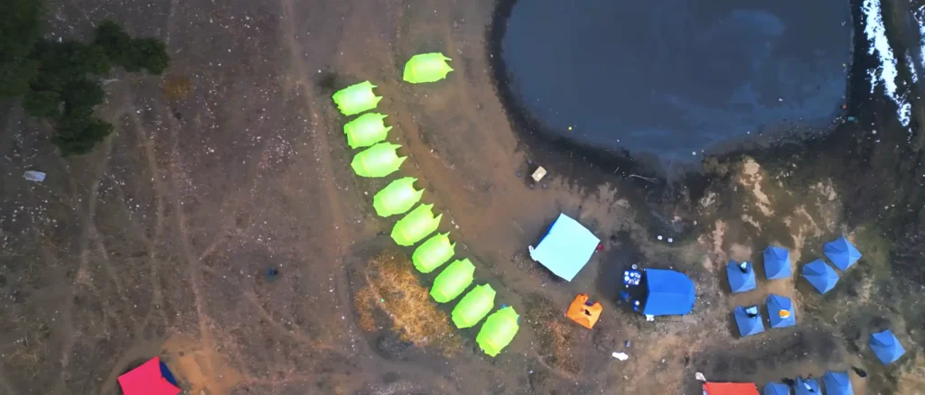 Brahmatal Trek lakeside campsite aerial view, Himalayan camping during Brahmatal winter trek, Brahmatal Trek tents near lake Uttarakhand, scenic trekking campsite India, best Himalayan trek camping experience